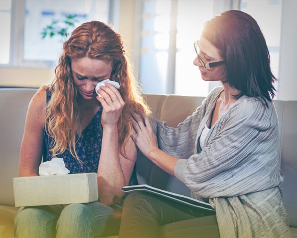 Девушка плачет, врач держит её за плечо